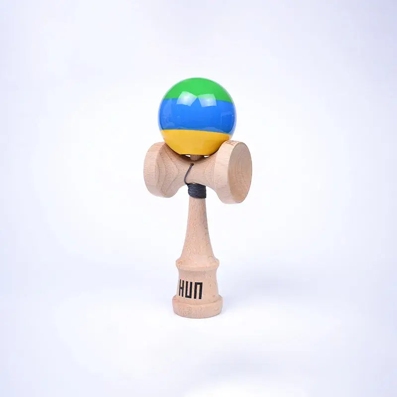 HUN Kendama Kylin Model with a glossy green, blue, and yellow striped ball, natural wood handle, and light background.