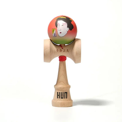 HUN kendama with an illustrated red-green ball, Japanese-style portrait artwork, red string, and natural wood handle, isolated on a light background.