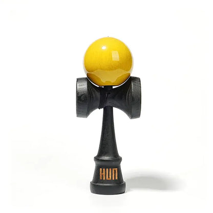 HUN kendama with a glossy yellow ball, black wooden handle, and light gray background.