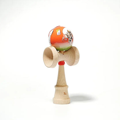HUN kendama with an illustrated orange-green ball, skull artwork, red string, and natural wood handle, isolated on a light background.