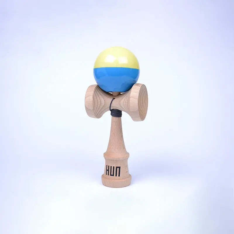 HUN Kendama Kylin Model with a glossy pale yellow and blue ball, natural wood handle, and light background.