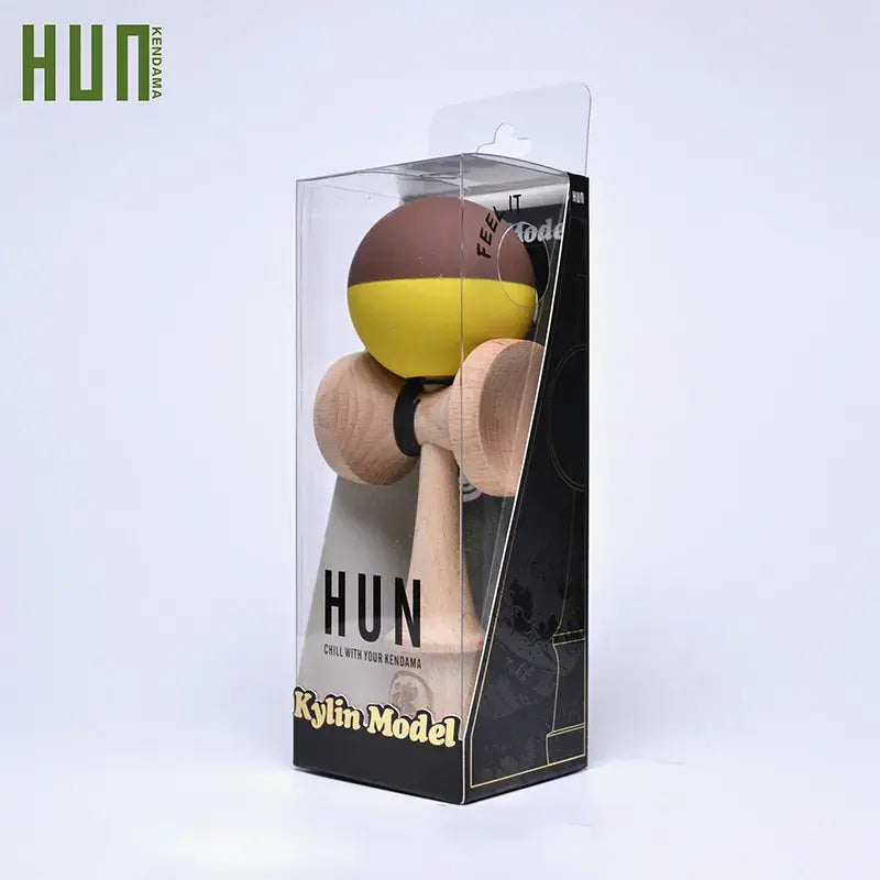 HUN Kendama Kylin Model packaged in a clear retail box, with a wooden kendama and brown-yellow ball on a light background.