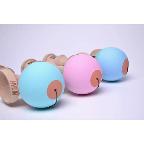 HUN Kendama Kylin Model pastel kendama balls in light blue, pink, and blue displayed in a row with wooden kendamas on a light background.