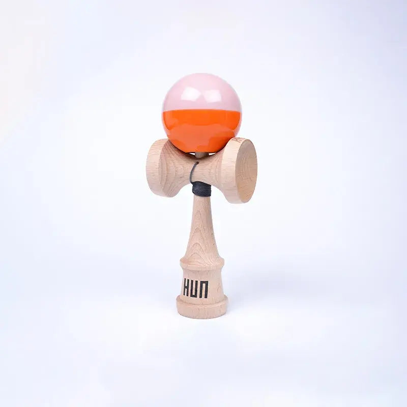 HUN Kendama Kylin Model with a glossy light pink and bright orange ball, natural wood handle, and light background.