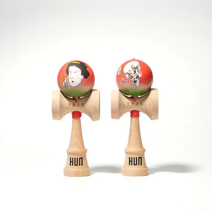 Two HUN kendamas with illustrated red-green balls, featuring Japanese-style portrait and skull artwork, displayed side by side on a light background.